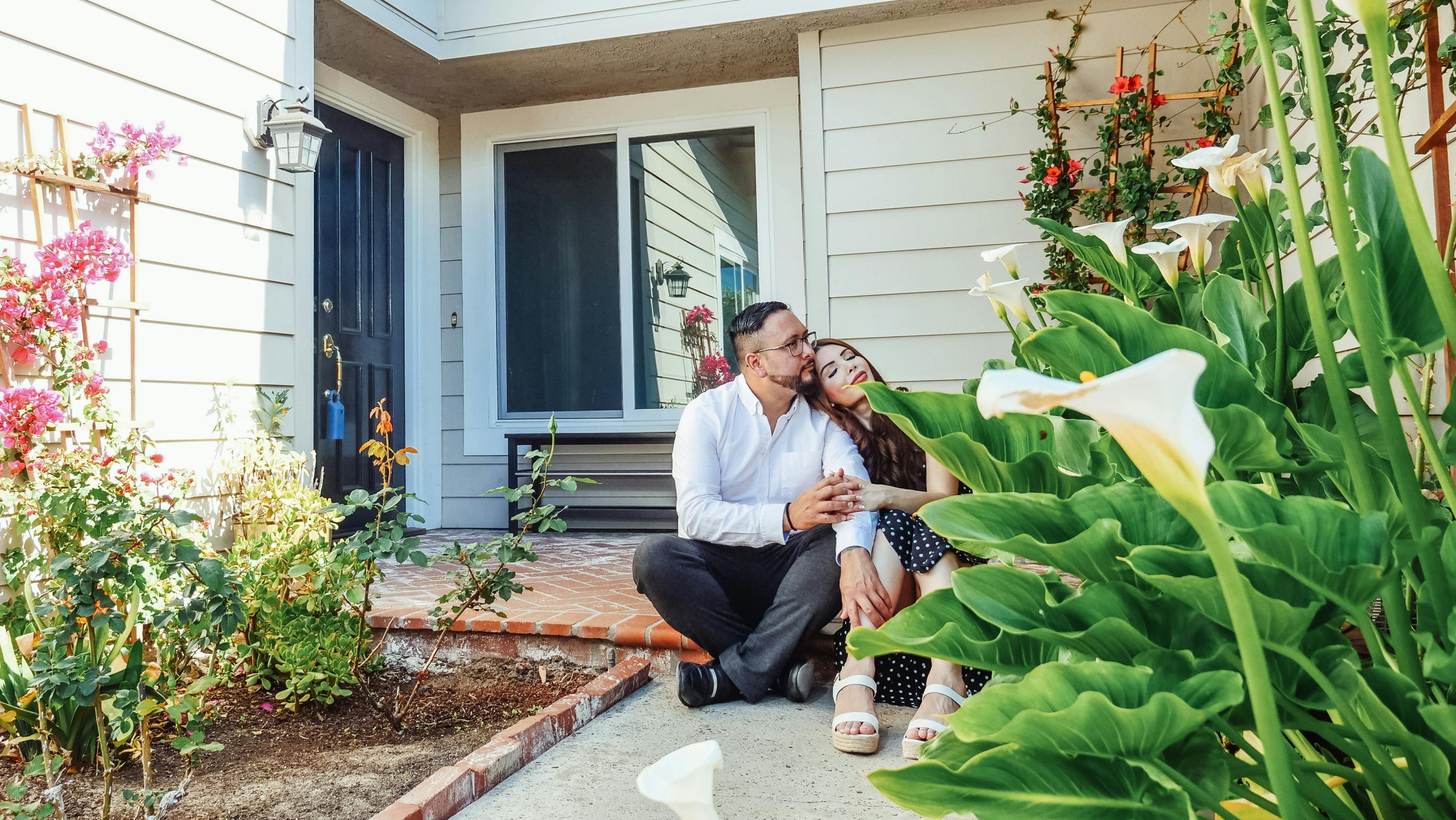 Happy home buyers sitting in front of their dream home for sale in South Florida.