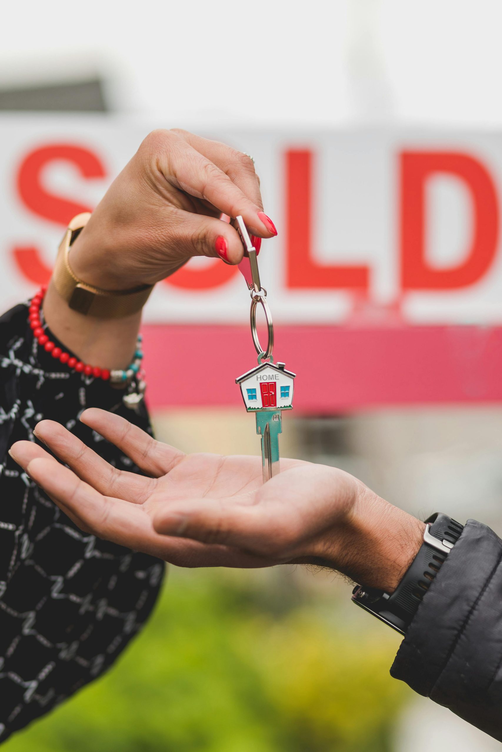 Seller and Real Estate Agent in front of a South Florida home with a red SOLD real estate sign.